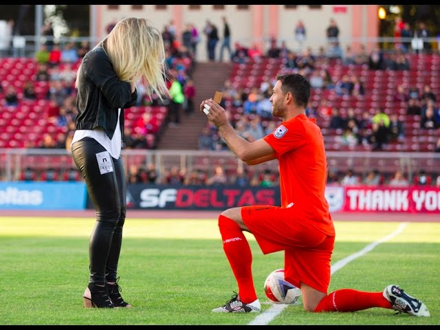 لحظة قيام لاعب كرة قدم بطلب الزواج من حبيبته على خط المنتصف لملعب كرة القدم قبيل بدء المباراة.