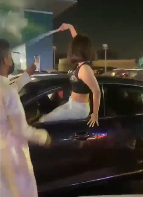 فتاة تخرج من نافذة سيارتها وتلوح بالعلم السعودي