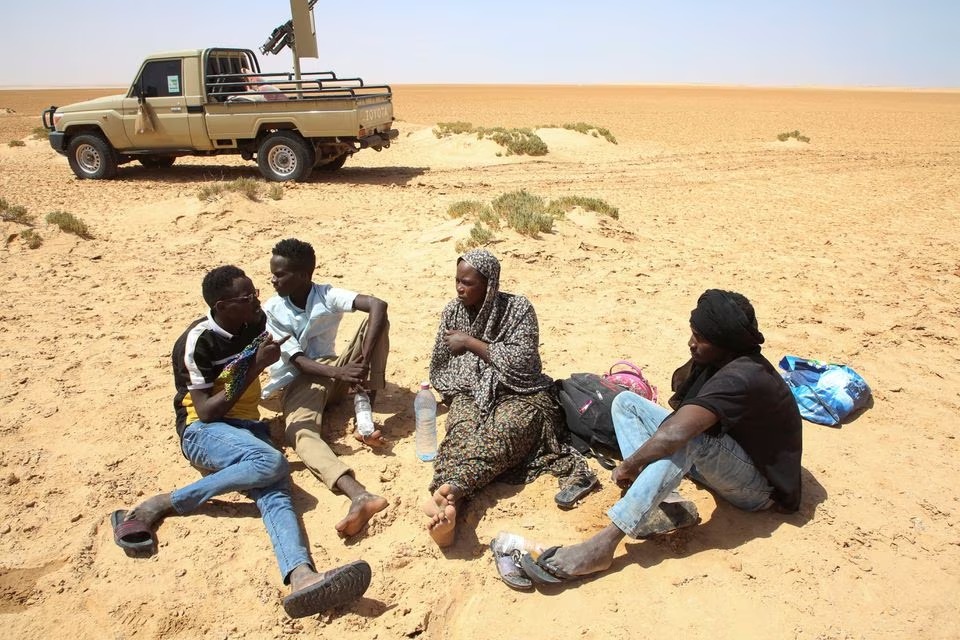 طفلة عمر ، ممرضة حامل تبلغ من العمر 26 عامًا من السودان ، تتحدث إلى مجموعة من الرجال حيث تقطعت بهم السبل في الصحراء على الحدود الليبية التونسية 