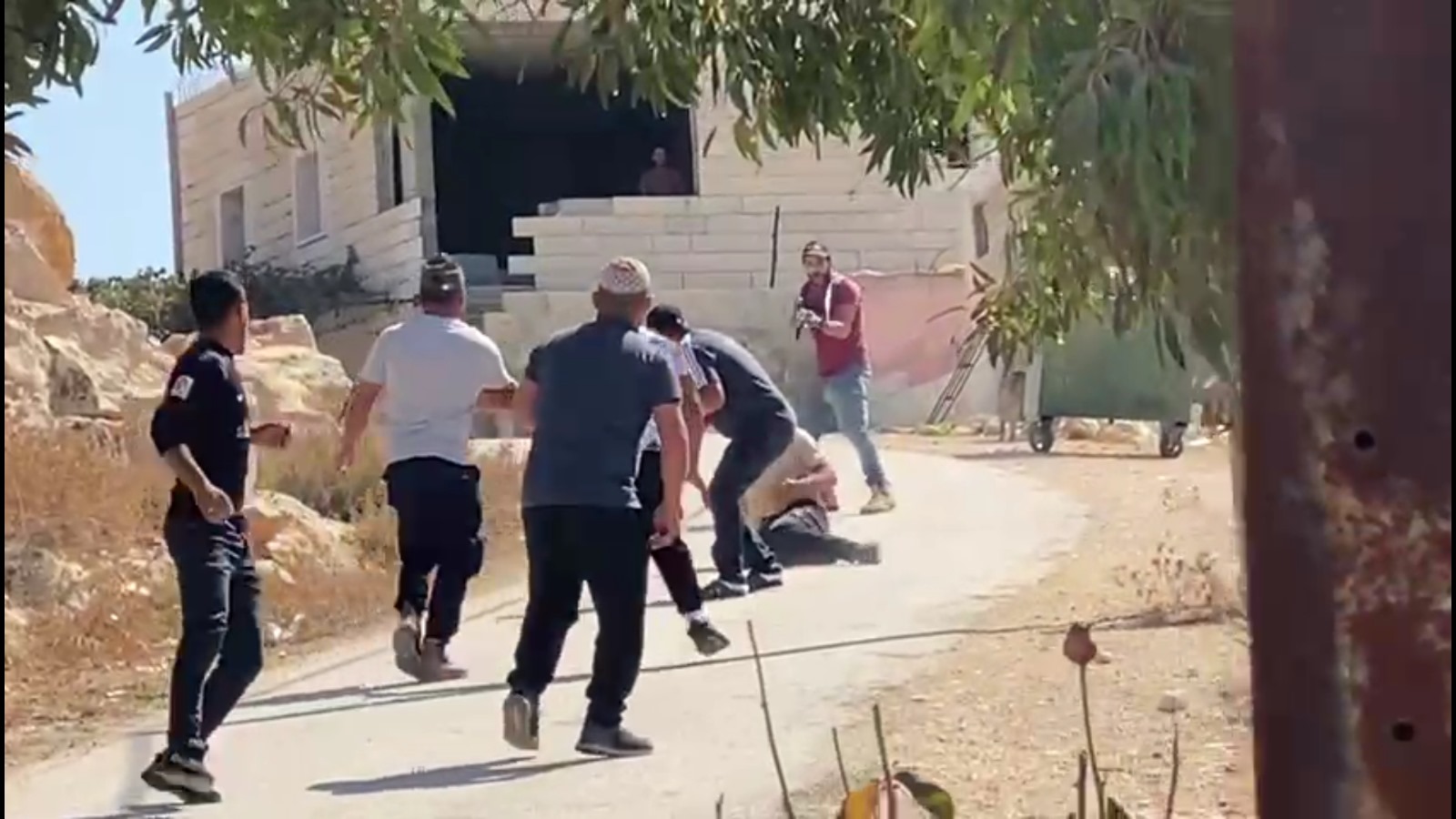 مستوطن يشهر السلاح في وجه شباب فلسطينيين استعدادا لإطلاق النار