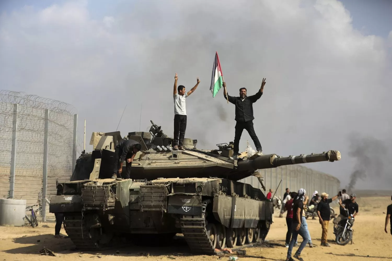 فلسطينيون يحتفلون فوق وحول دبابة إسرائيلية مدمرة قرب سياج قطاع غزة شرق خان يونس