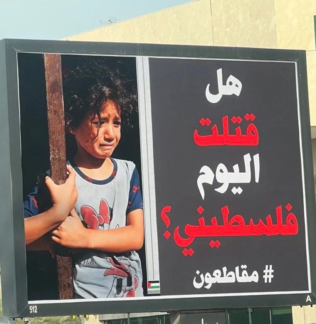 لافتة في شوارع الكويت عليها صورة طفلة فلسطينية، وكتب عليها "هل قتلت اليوم فلسطيني؟" وعليها هاشتاغ مقاطعون