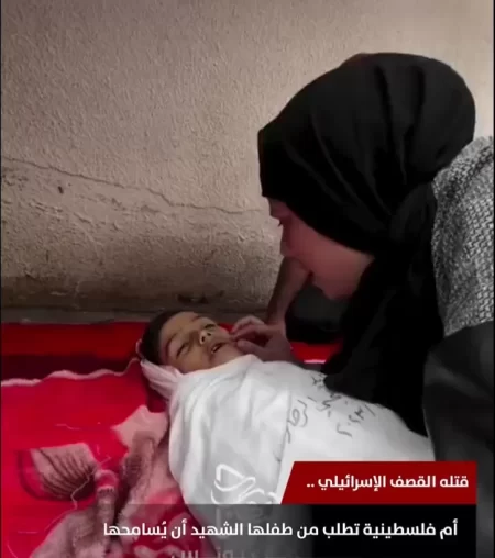 سيدة فلسطينية تجلس أمام جثمان طفلها الشهيد