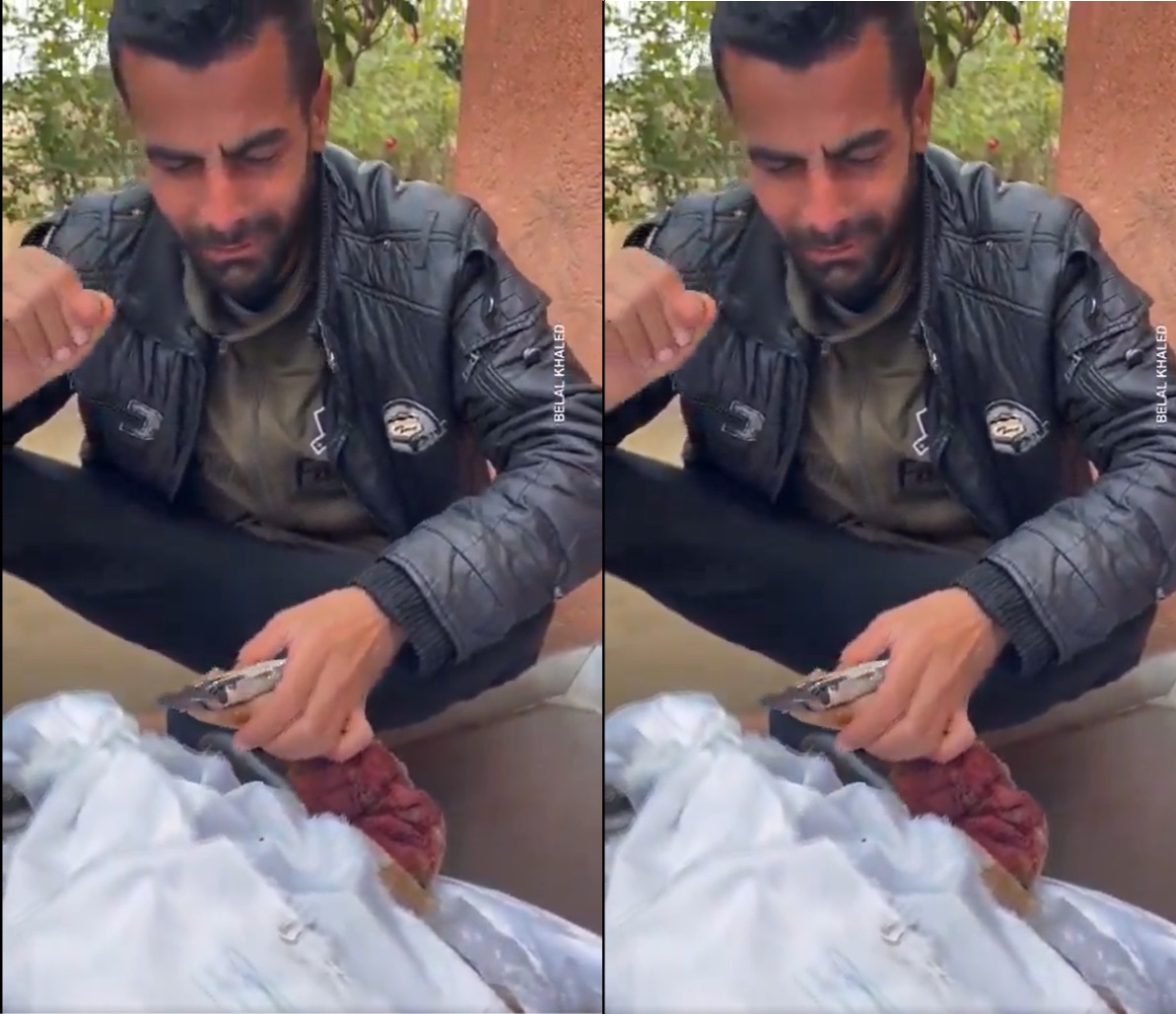 أب فلسطيني يضع قطعة حلوى في يد ابنه الشهيد