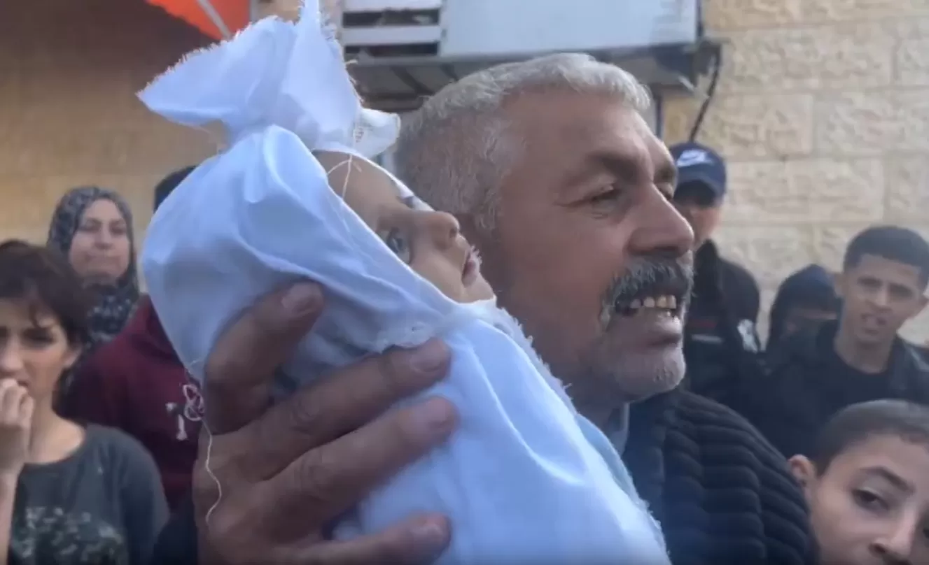 فلسطيني يحمل جثمان حفيده